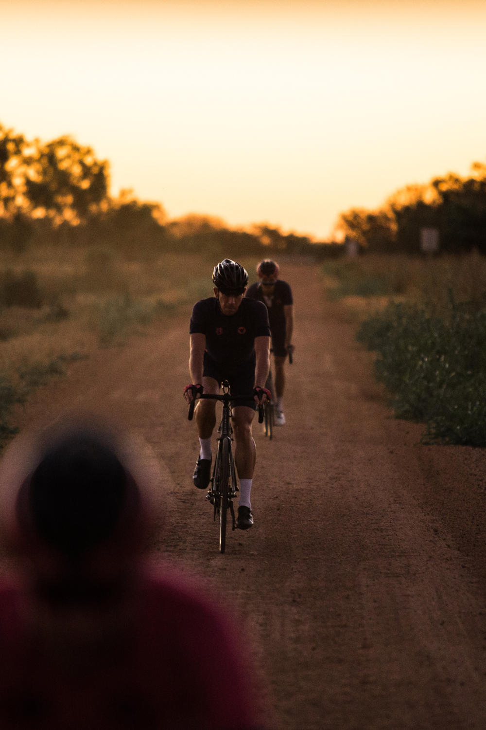 ManRide cyclists riding a gravel road at sunset